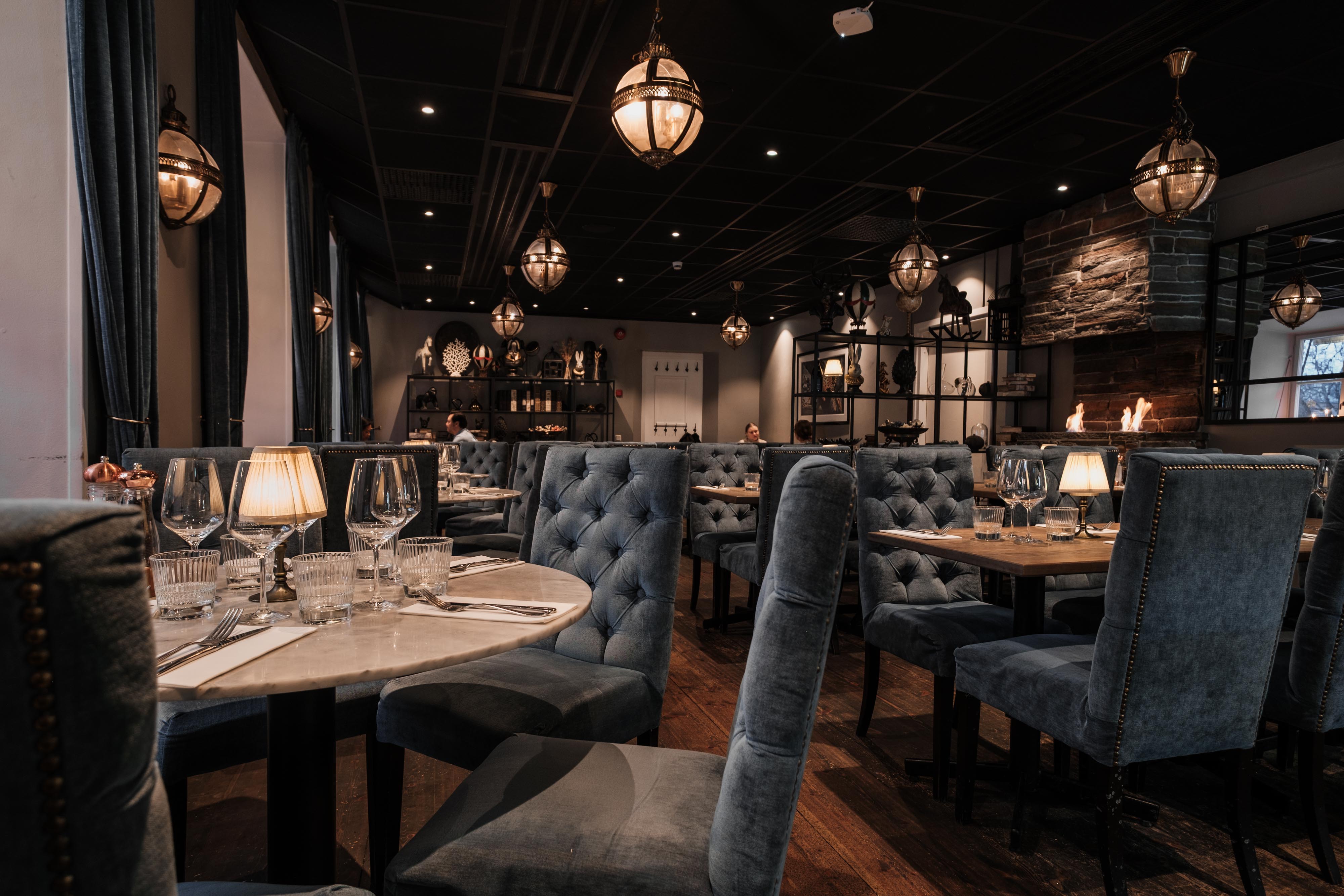 Set tables with candlelight and blue velvet chairs in the Villa Romana restaurant in Uppsala