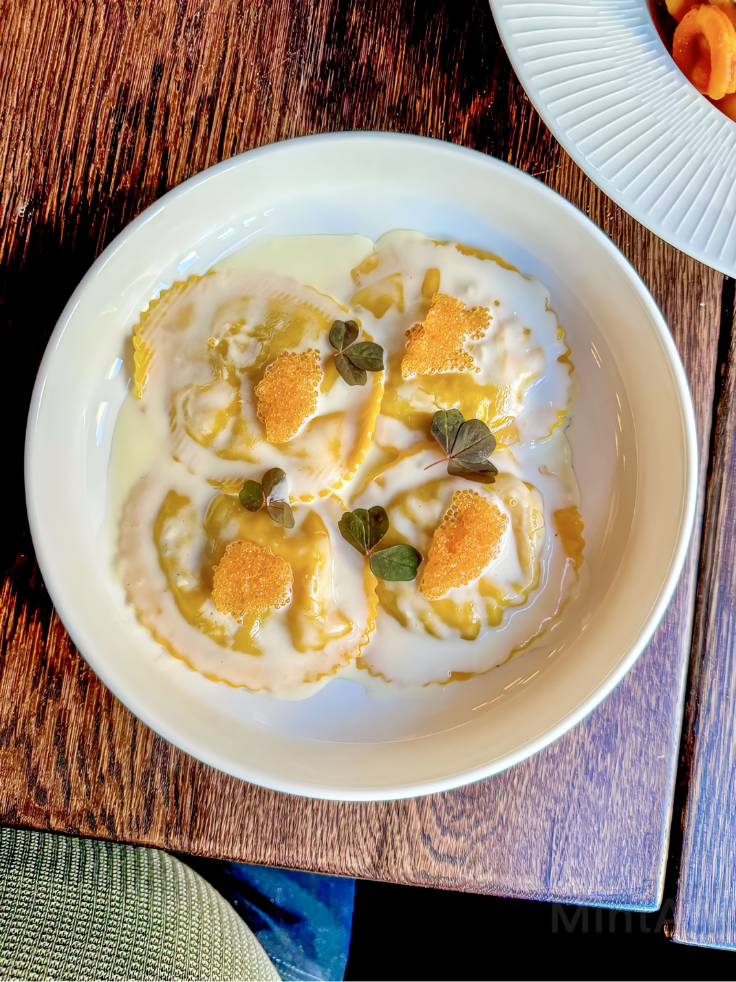 Handgjord ravioli med löjrom i en vit tallrik på ett träbord