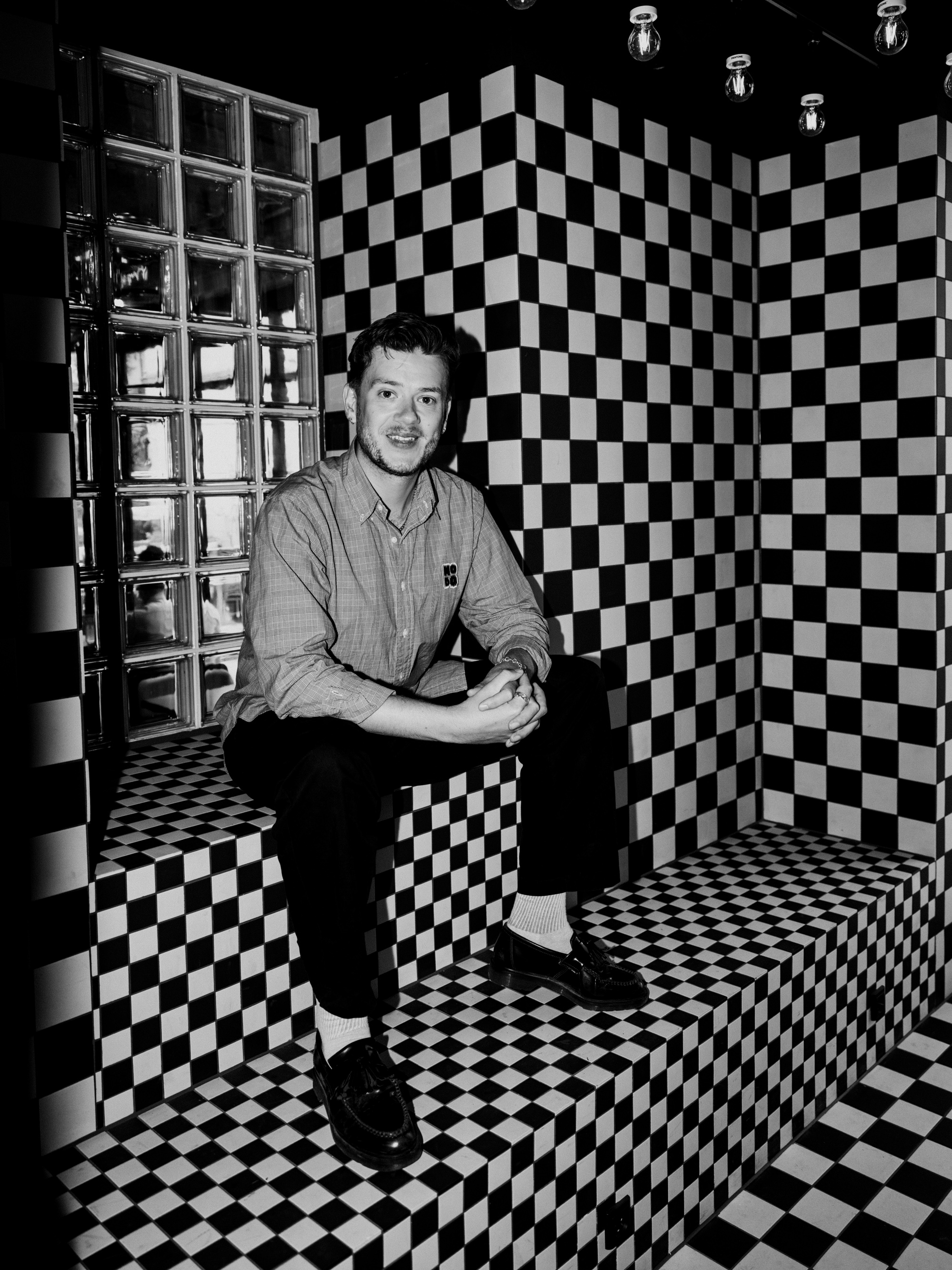 Man sits on checkered bench in room.