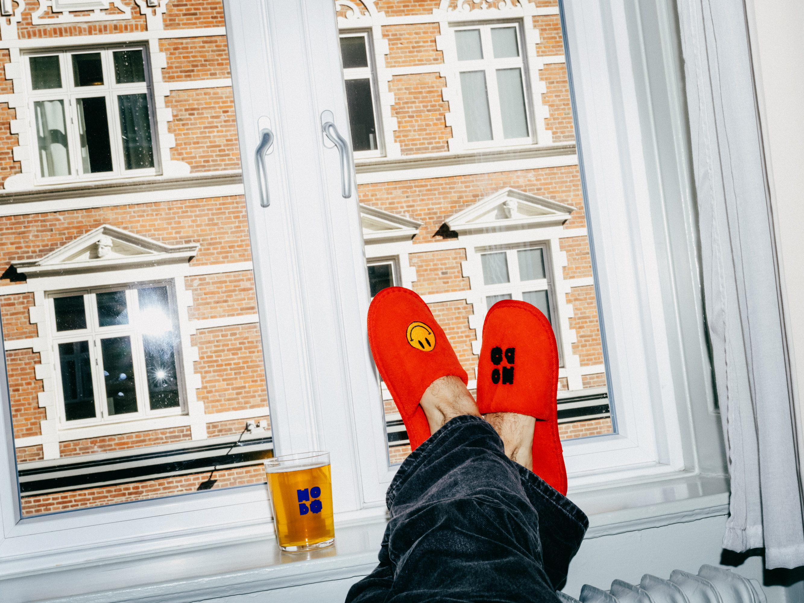Feet in red Hobo slippers resting in a window with a beer and a view of the street