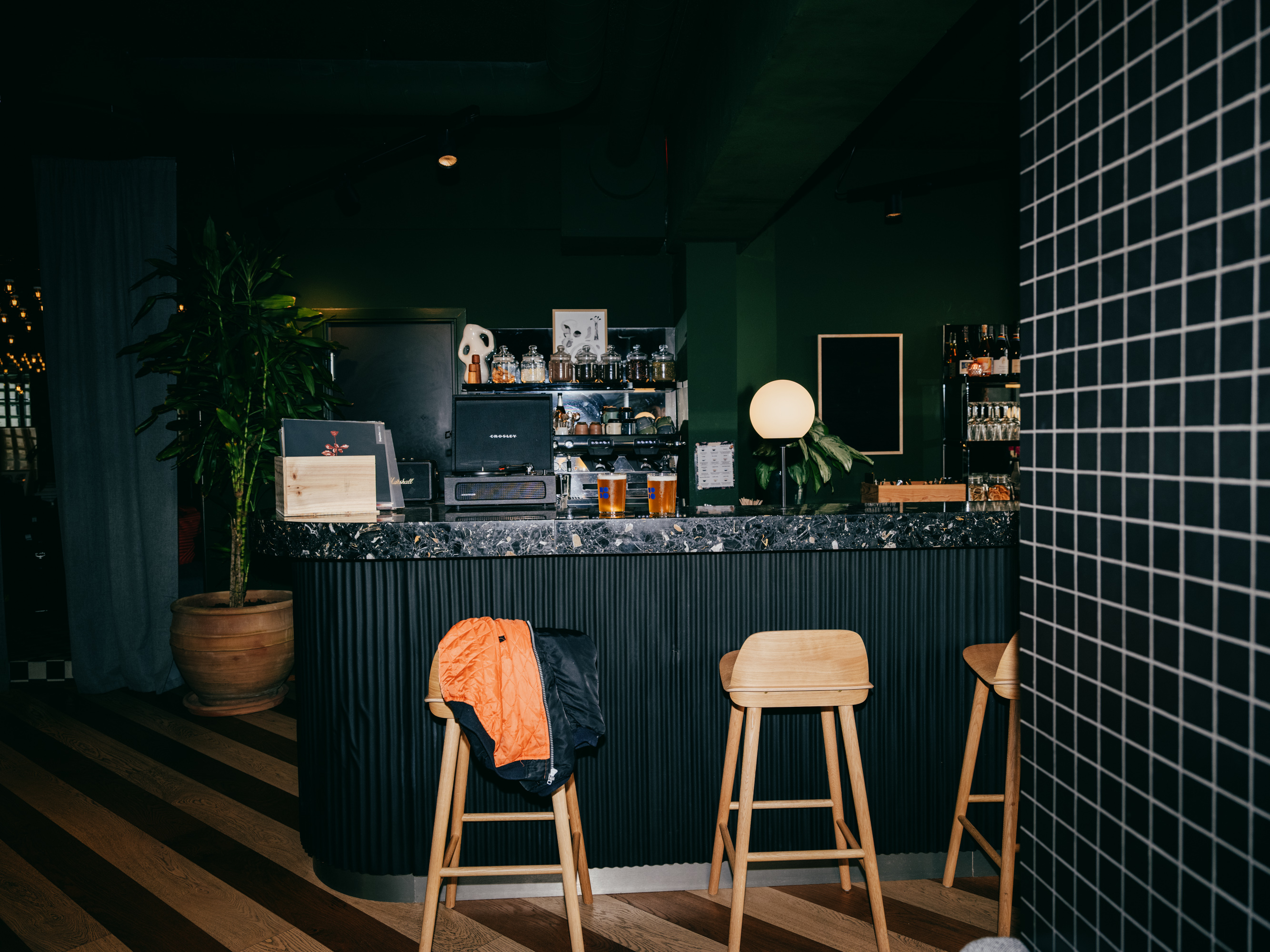 Bar counter with black terrazzo top, bar stools and a striped floor