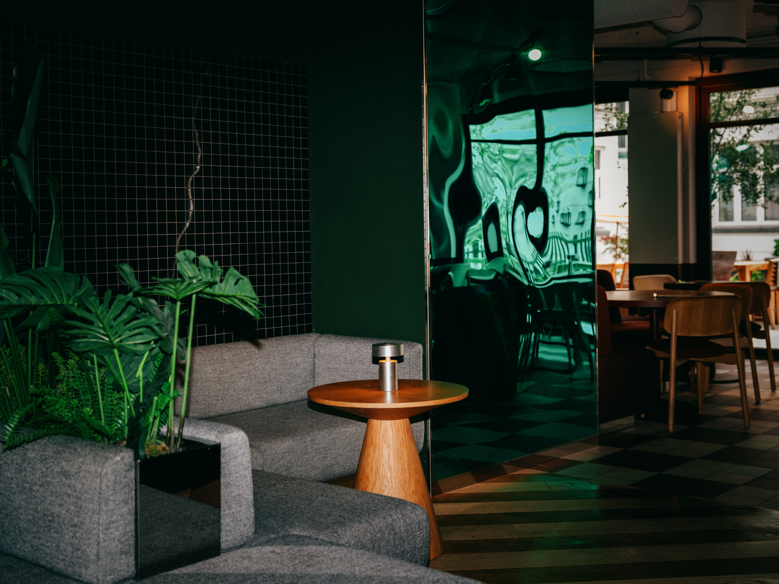 Loungehjørne med grå sofa, planter og et lille sidebord