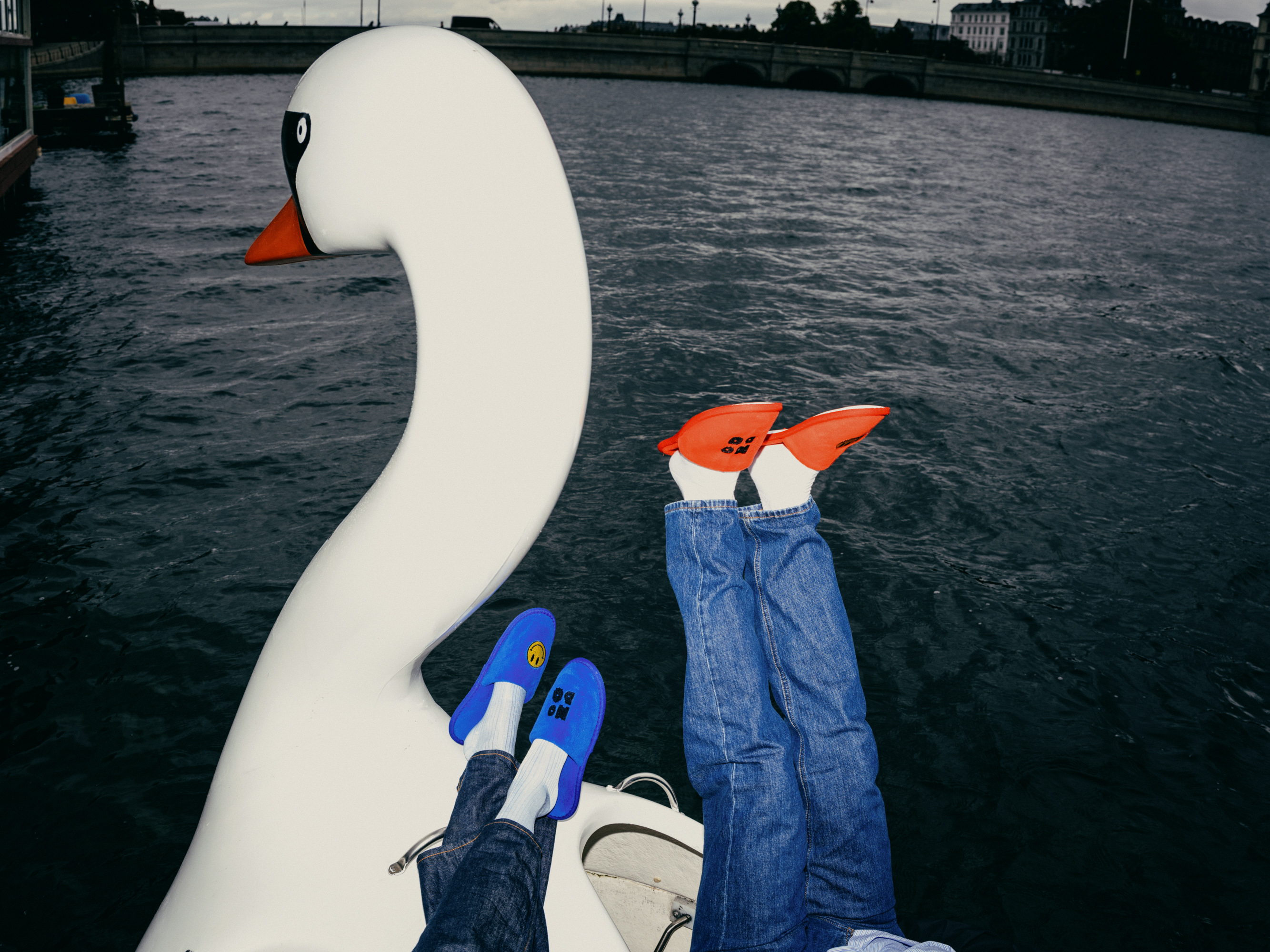 Feet in Hobo slippers on a swan pedal boat on the water