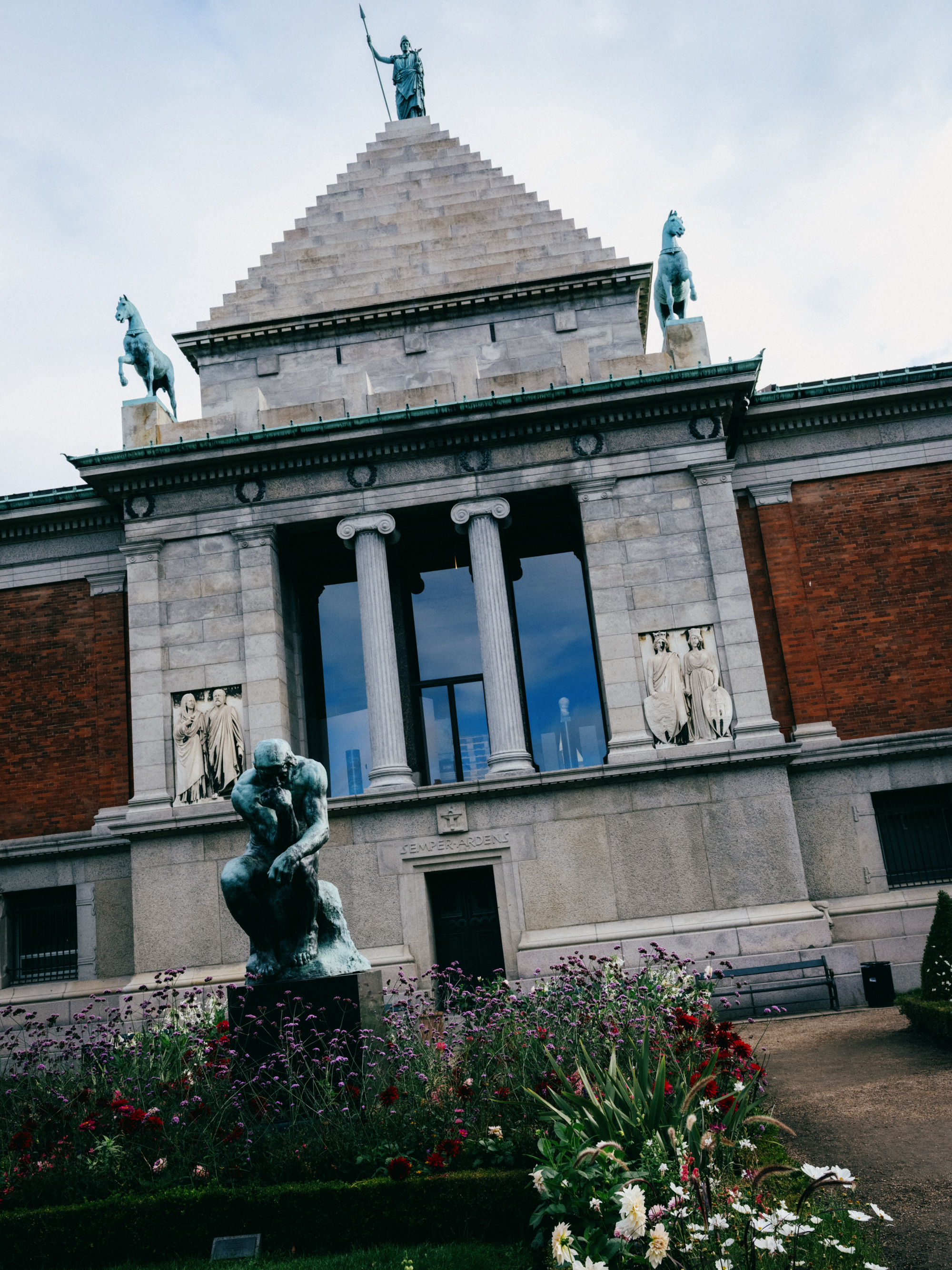 Classical museum building with a bronze statue in front of the garden