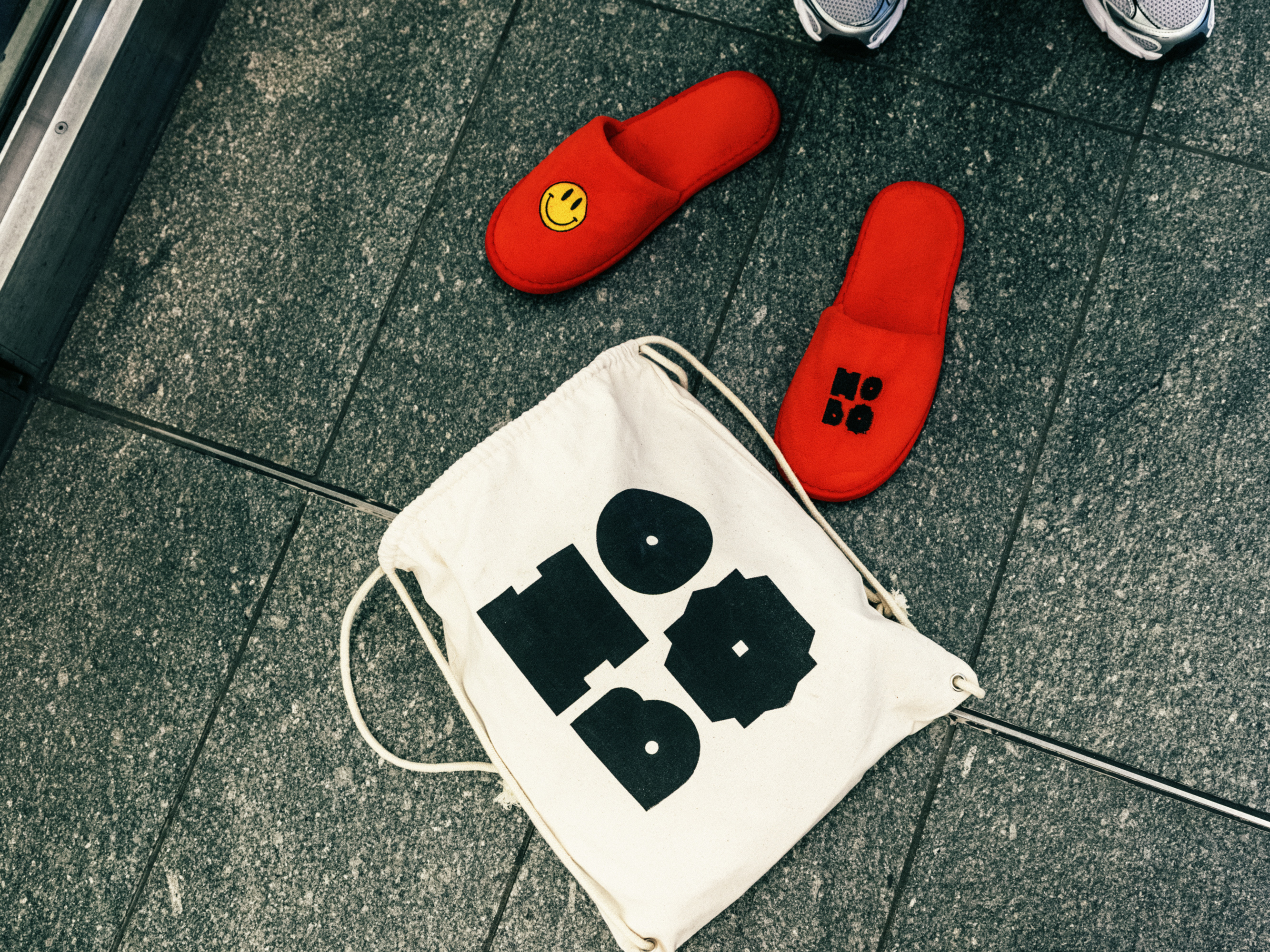 Red Hobo slippers and a Hobo tote bag on a stone floor