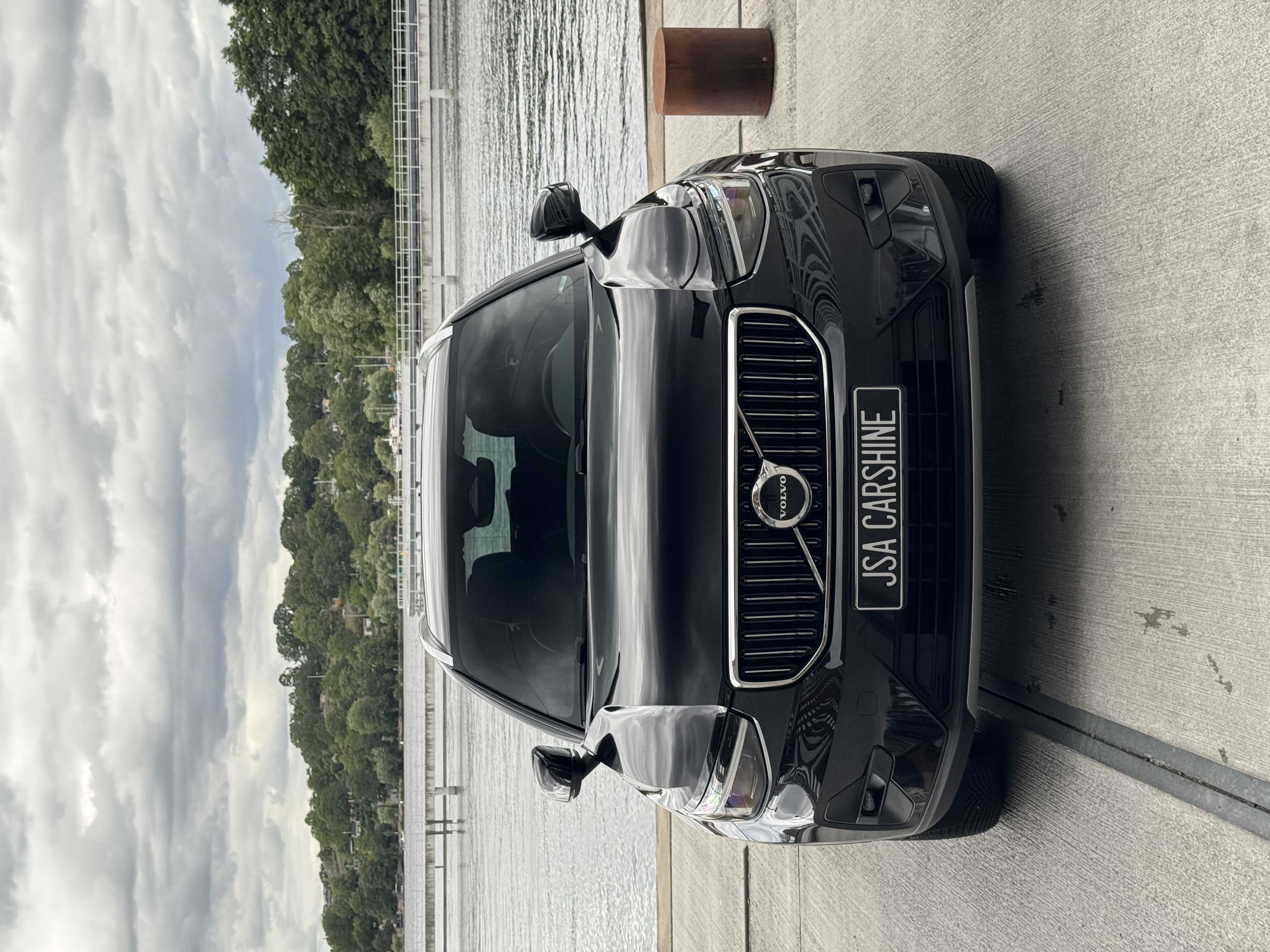Nyrekondad svart Volvo med JSA Carshine-skylt vid vattnet