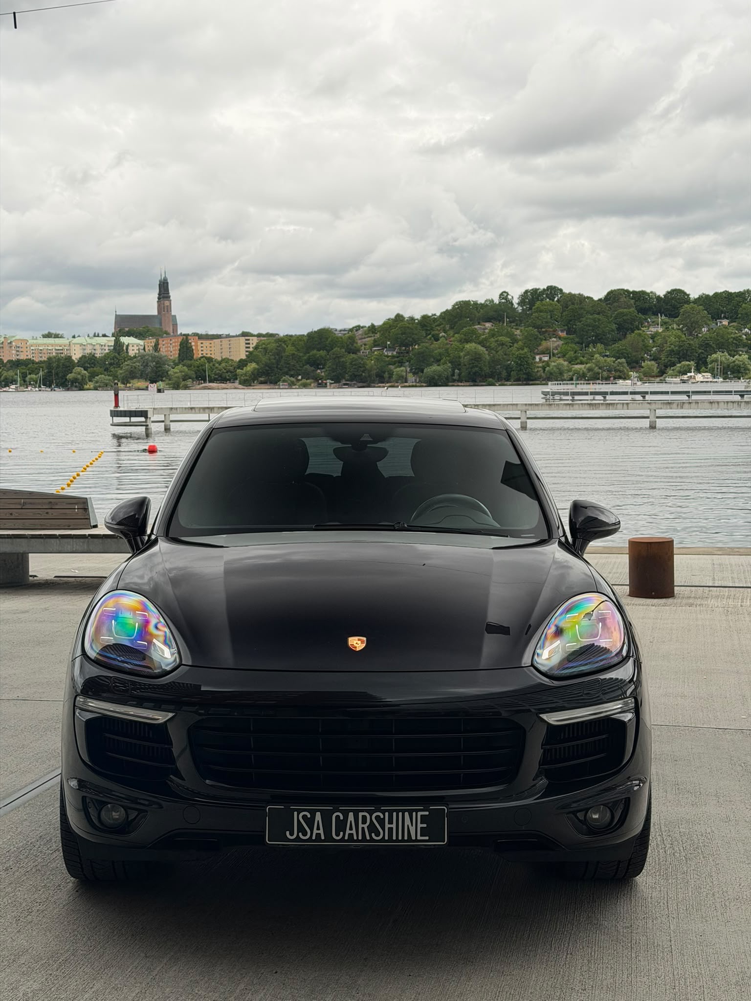 Svart Porsche Cayenne med JSA Carshine-skylt vid vattnet