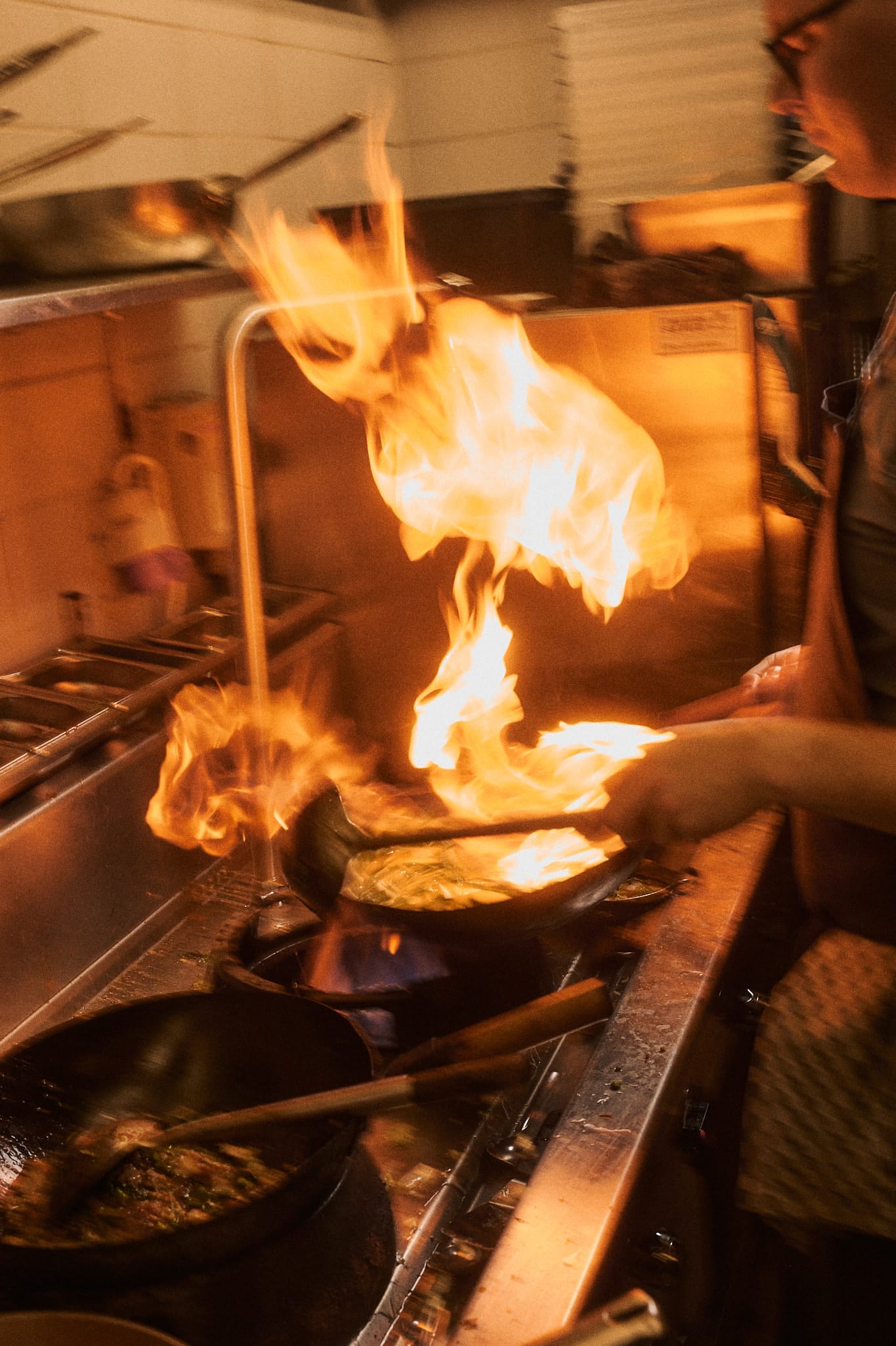 Chef stir-frying over high flames in Farang's kitchen