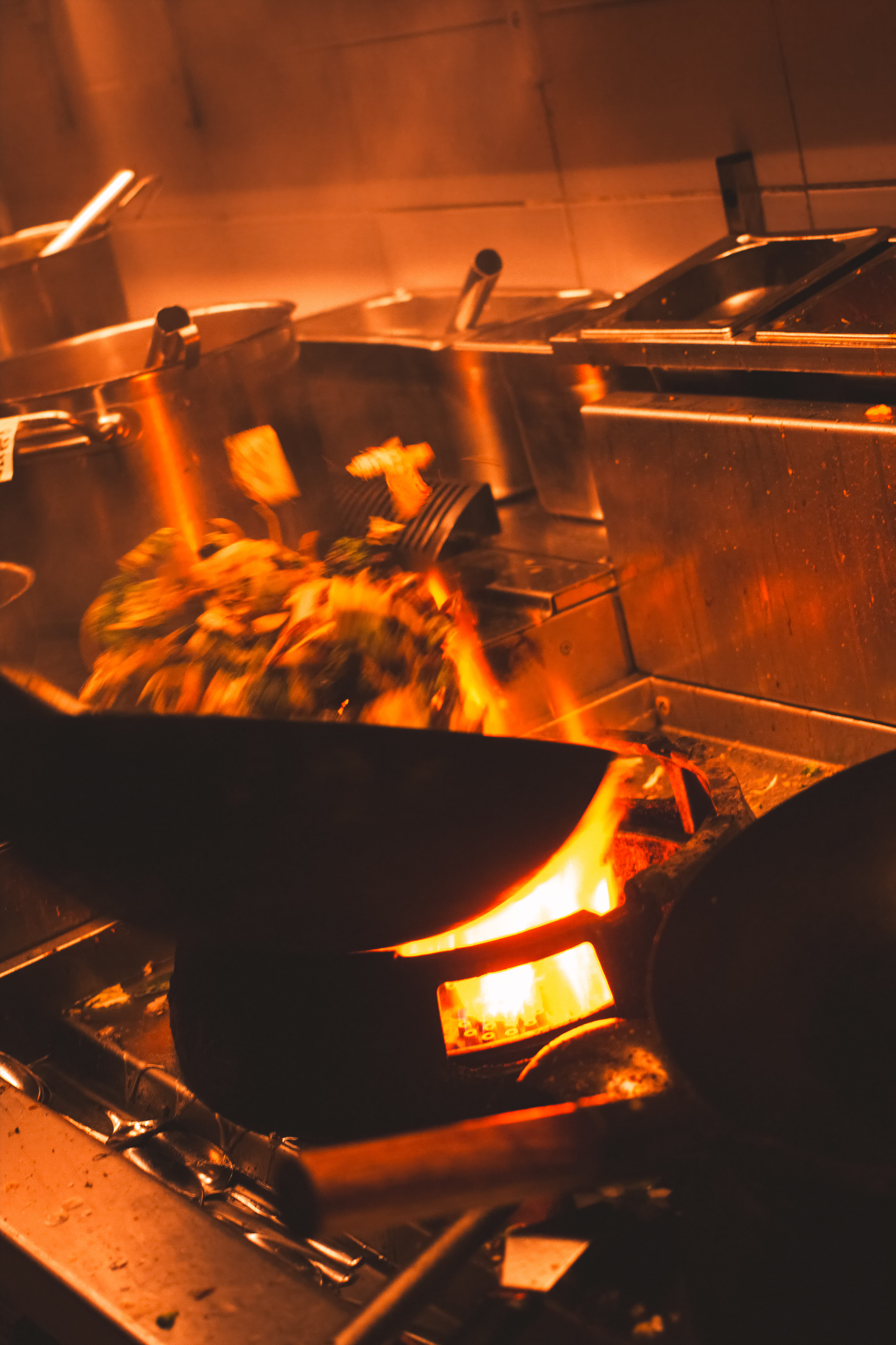 Vegetables being stir-fried over an open flame in the kitchen